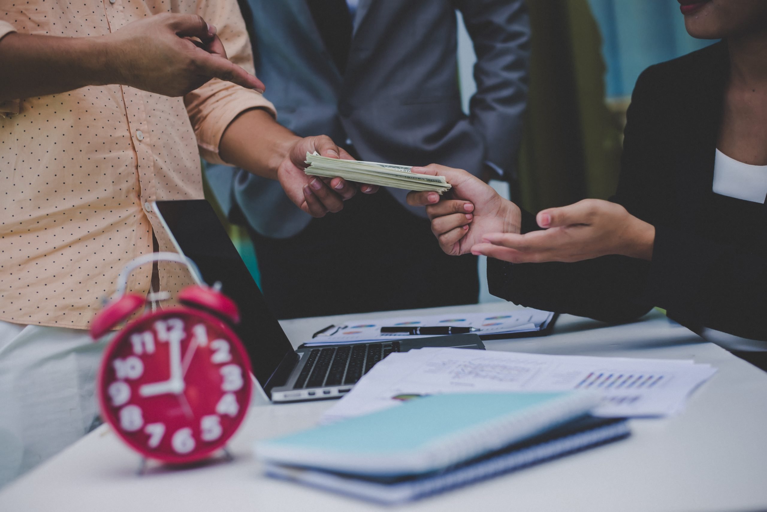 Two professionals at a meeting, discussing a report and using a phone, with a focus on financial services by a licensed money lender in Singapore